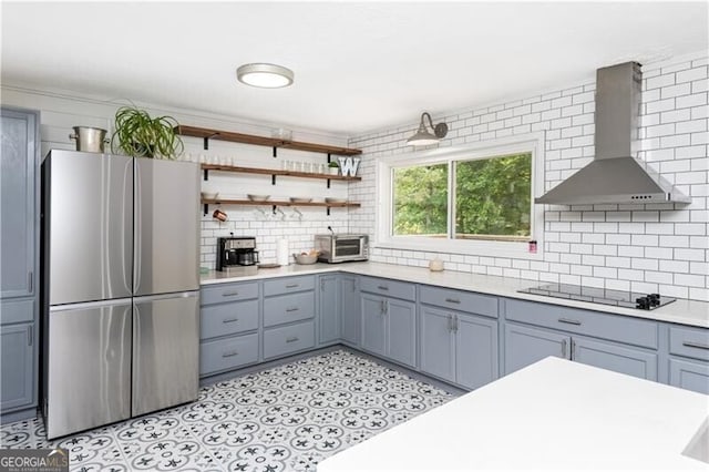 kitchen with stainless steel fridge, wall chimney exhaust hood, tasteful backsplash, and black electric cooktop