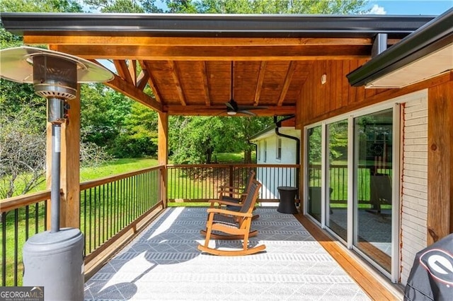 wooden terrace with ceiling fan and a lawn