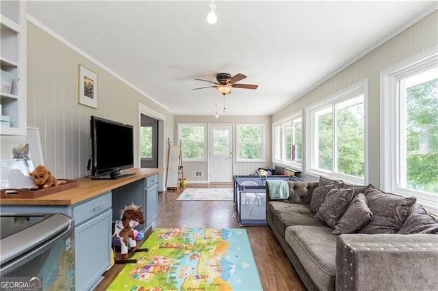 living room with crown molding, dark wood-type flooring, and ceiling fan