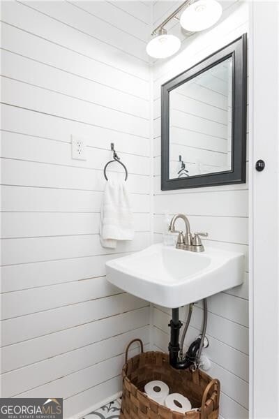 bathroom featuring wood walls and sink