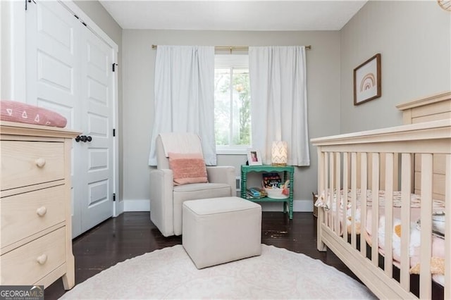 bedroom featuring a nursery area and dark hardwood / wood-style flooring