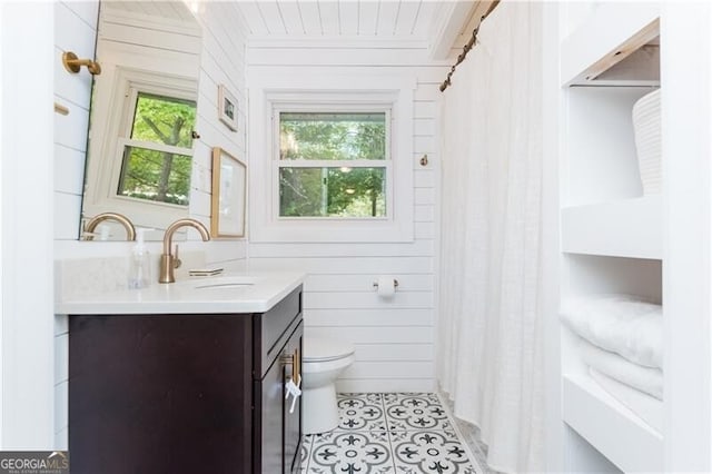 bathroom with vanity, toilet, wood walls, and tile patterned flooring