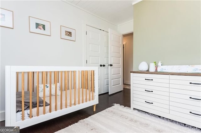 bedroom featuring dark hardwood / wood-style floors and a crib