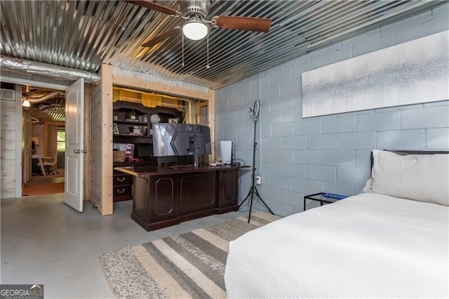 bedroom with concrete block wall, a ceiling fan, and concrete flooring