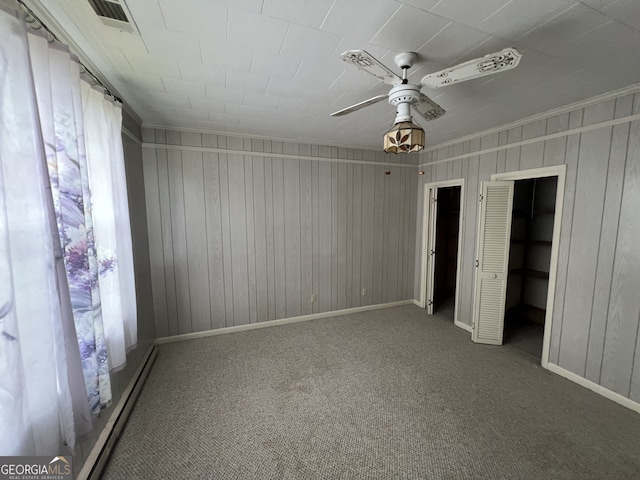 unfurnished bedroom featuring a closet, a walk in closet, ceiling fan, and carpet floors