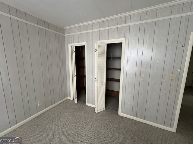 unfurnished bedroom featuring wood walls, carpet, and crown molding