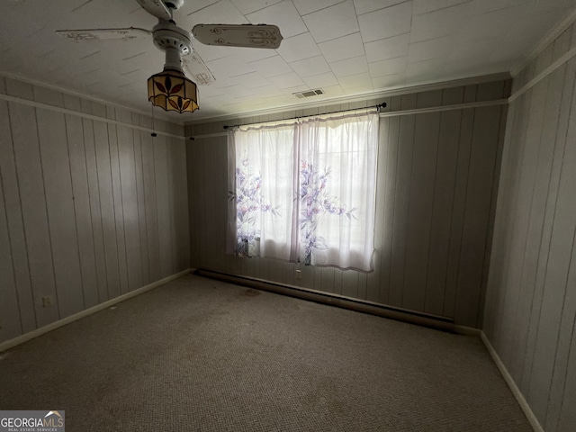 carpeted spare room with ceiling fan and wood walls