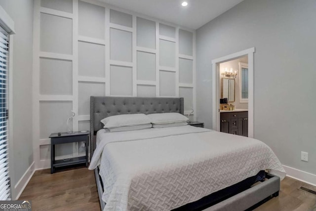 bedroom featuring ensuite bath, wood-type flooring, and a notable chandelier