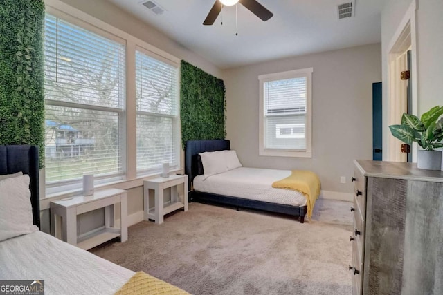 bedroom featuring ceiling fan, light carpet, and multiple windows