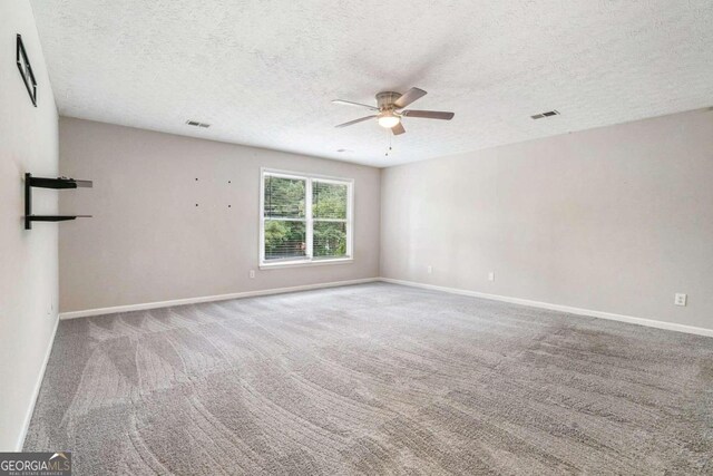 carpeted spare room featuring a textured ceiling and ceiling fan