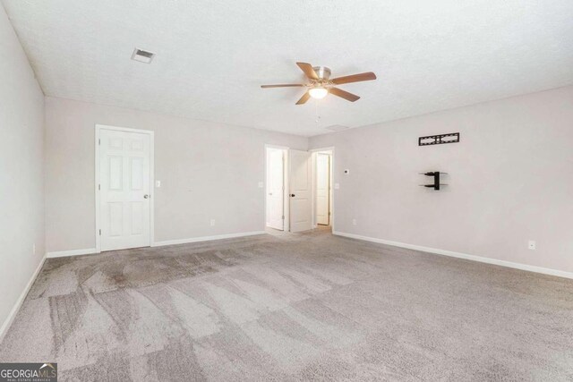 spare room with a textured ceiling, ceiling fan, and carpet