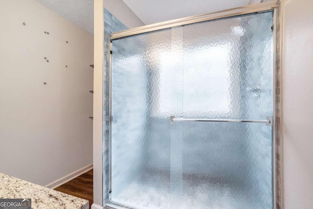 bathroom featuring an enclosed shower, hardwood / wood-style flooring, and a healthy amount of sunlight