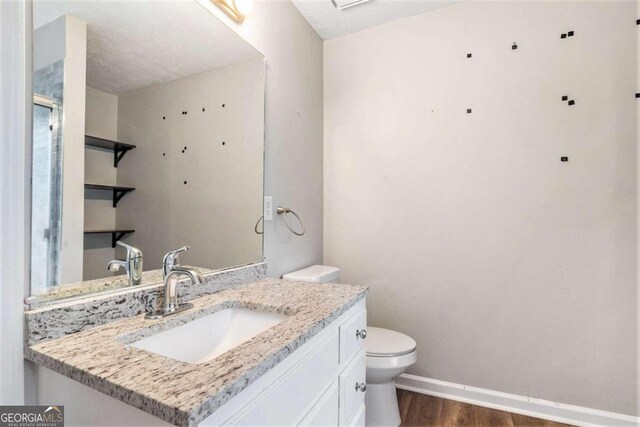 bathroom with a textured ceiling, vanity, toilet, and hardwood / wood-style floors