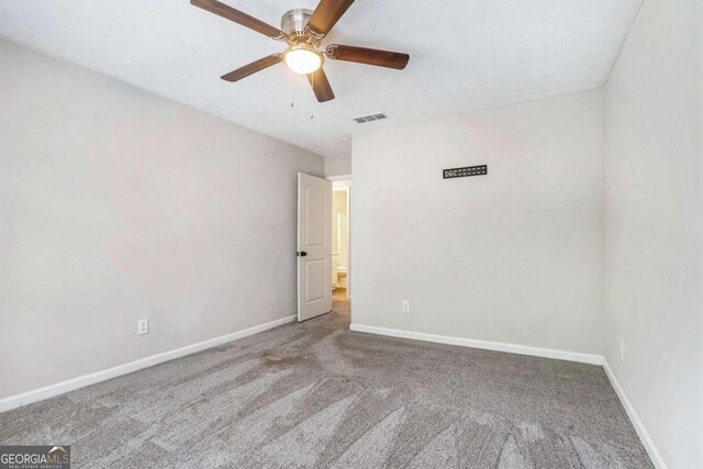 spare room featuring a textured ceiling, ceiling fan, and carpet