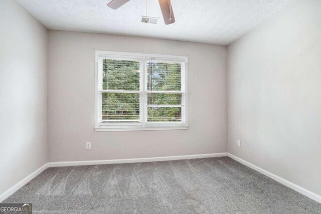 unfurnished room with a textured ceiling, ceiling fan, and carpet flooring