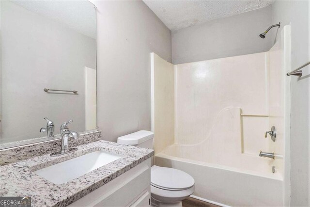 full bathroom with a textured ceiling, vanity, toilet, and shower / bathtub combination