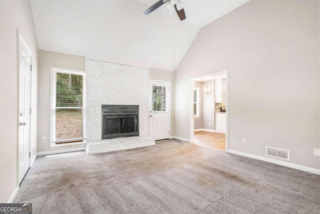 unfurnished living room featuring high vaulted ceiling, ceiling fan, light colored carpet, and a stone fireplace