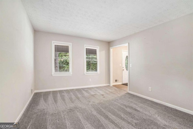 spare room featuring a textured ceiling and light colored carpet