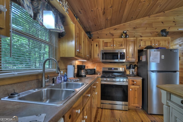 kitchen with light hardwood / wood-style flooring, wood walls, sink, appliances with stainless steel finishes, and lofted ceiling