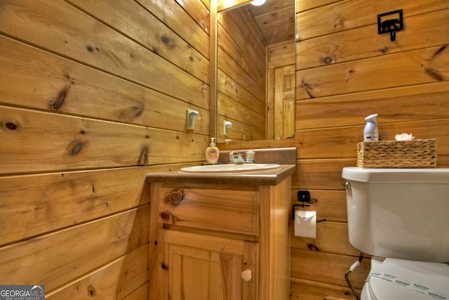 bathroom with toilet, wooden walls, and vanity