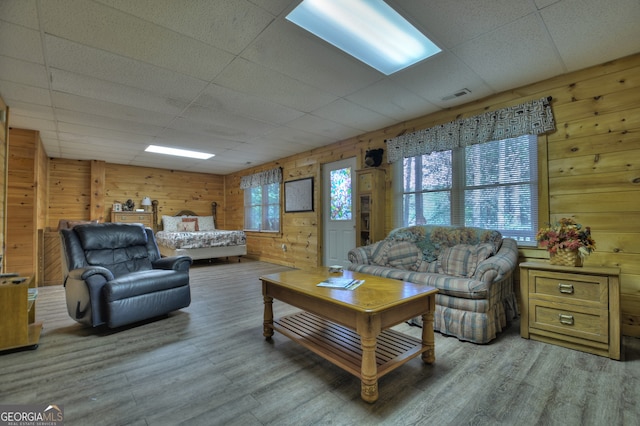 living room featuring wood walls, wood-type flooring, and a drop ceiling