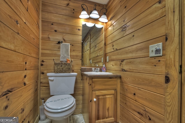 bathroom featuring vanity, toilet, and wooden walls