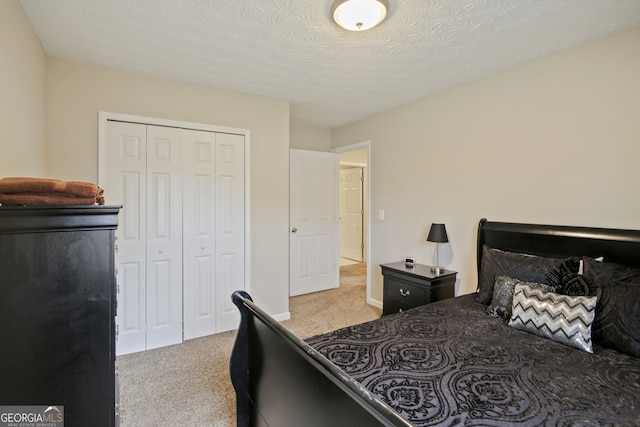 carpeted bedroom with a textured ceiling and a closet