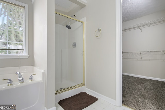 bathroom featuring shower with separate bathtub and a textured ceiling