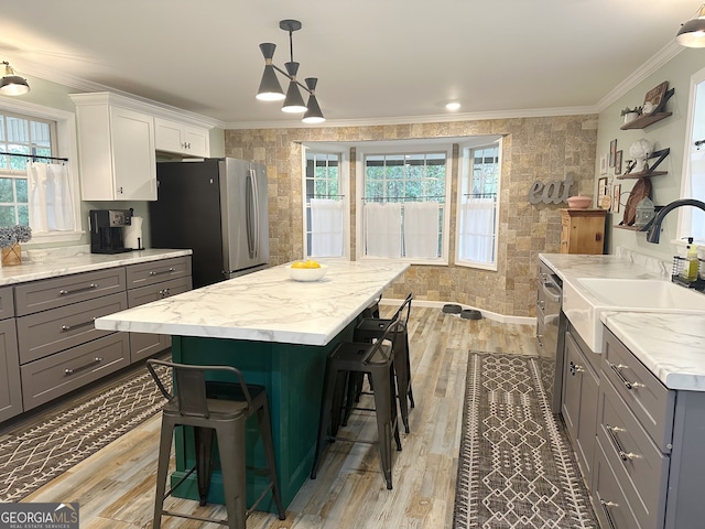 kitchen with white cabinets, appliances with stainless steel finishes, a kitchen bar, and light hardwood / wood-style flooring