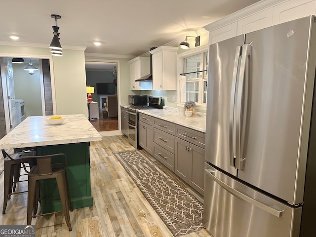 kitchen with appliances with stainless steel finishes, white cabinetry, pendant lighting, and light hardwood / wood-style floors