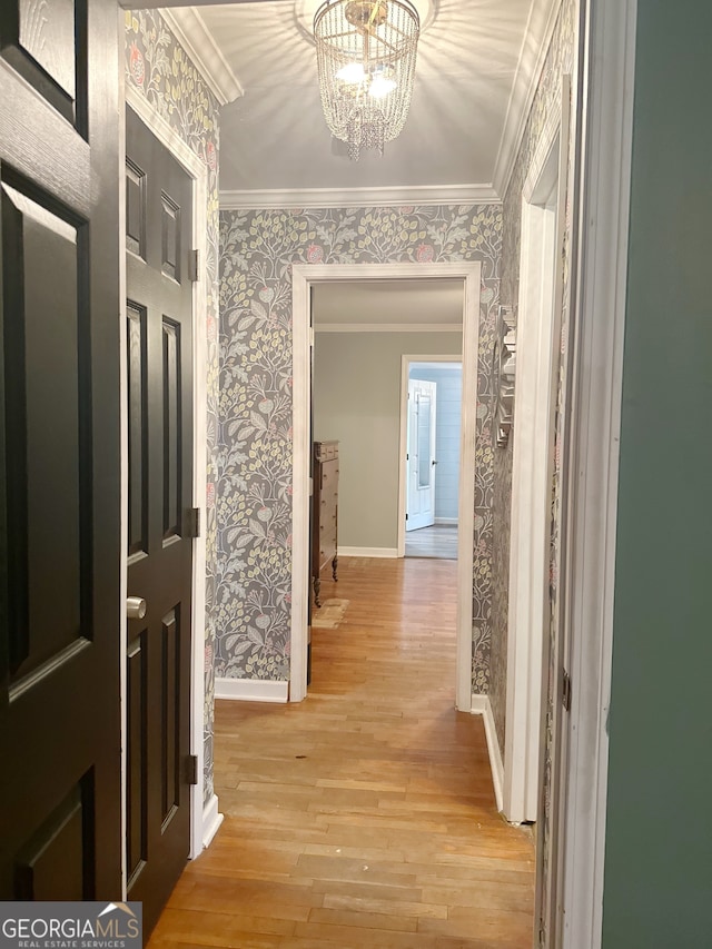 hall featuring crown molding, light hardwood / wood-style flooring, and a notable chandelier