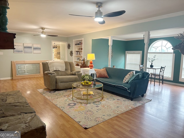 living room with built in shelves, ceiling fan, ornamental molding, and light wood-type flooring