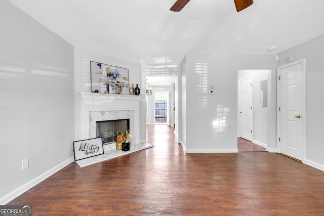 unfurnished living room featuring a textured ceiling, ceiling fan, a fireplace, and dark hardwood / wood-style flooring