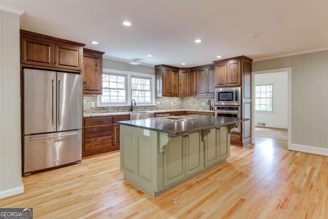 kitchen with crown molding, a kitchen island, light hardwood / wood-style flooring, and appliances with stainless steel finishes