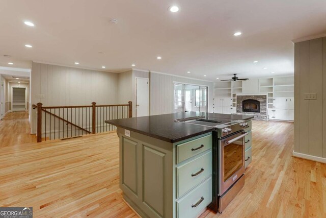 kitchen with a fireplace, green cabinets, electric stove, light hardwood / wood-style flooring, and a kitchen island