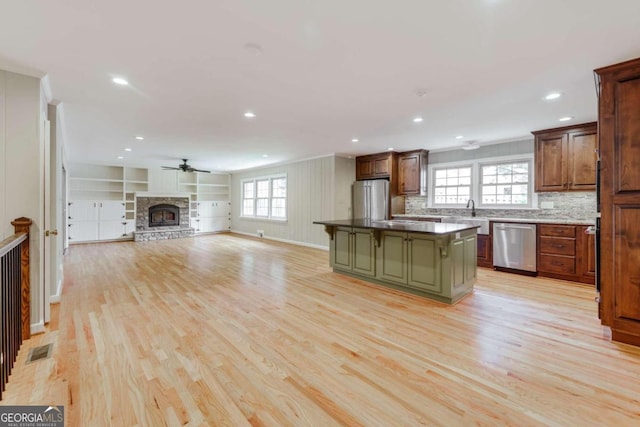 kitchen with a healthy amount of sunlight, dishwasher, a center island, and a stone fireplace