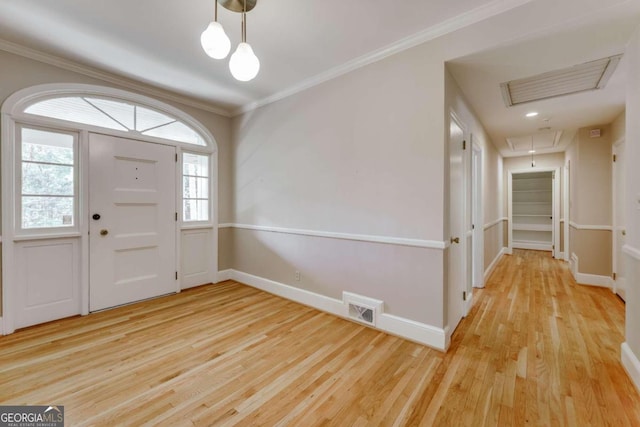 entryway with visible vents, light wood finished floors, and ornamental molding