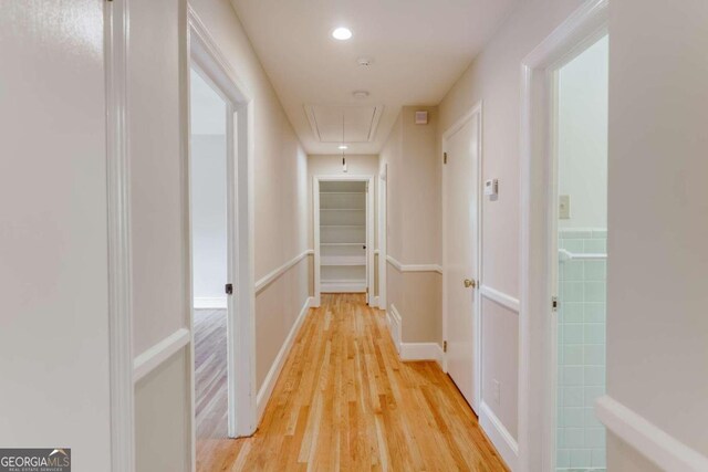 corridor with tile walls and light hardwood / wood-style floors