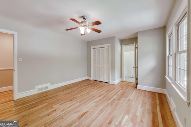 unfurnished bedroom featuring baseboards, visible vents, light wood finished floors, ceiling fan, and a closet