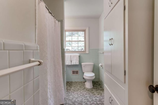 full bath with visible vents, a wainscoted wall, toilet, a shower with shower curtain, and tile walls