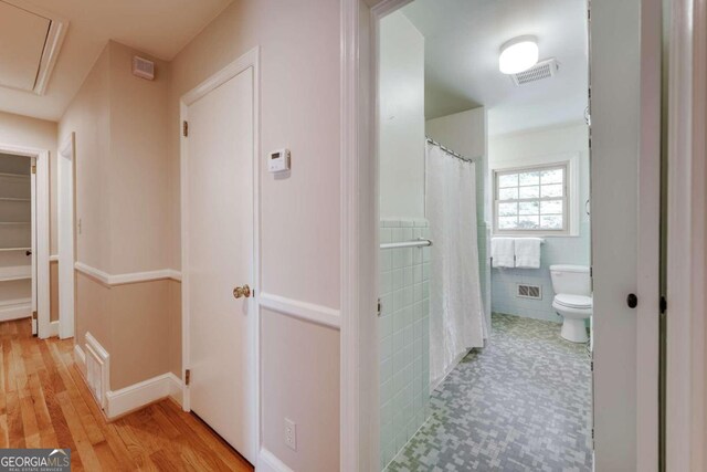 hallway with tile walls and light hardwood / wood-style flooring