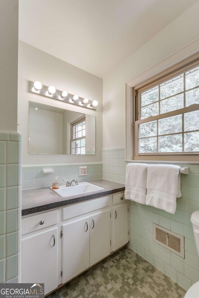 bathroom featuring a healthy amount of sunlight, backsplash, toilet, and vanity