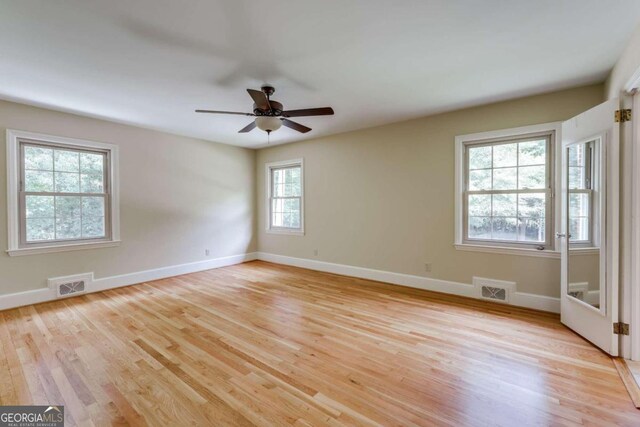 empty room featuring plenty of natural light, ceiling fan, and light hardwood / wood-style floors