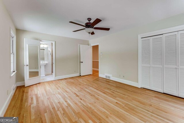 unfurnished bedroom featuring a closet, connected bathroom, ceiling fan, and light hardwood / wood-style floors