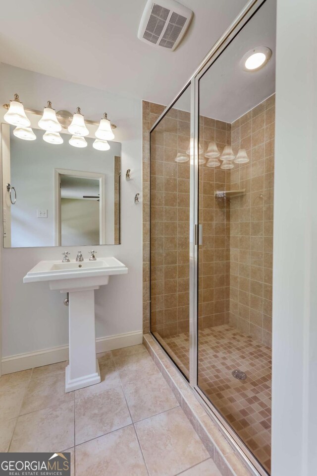 bathroom featuring a shower with door, sink, and tile patterned floors