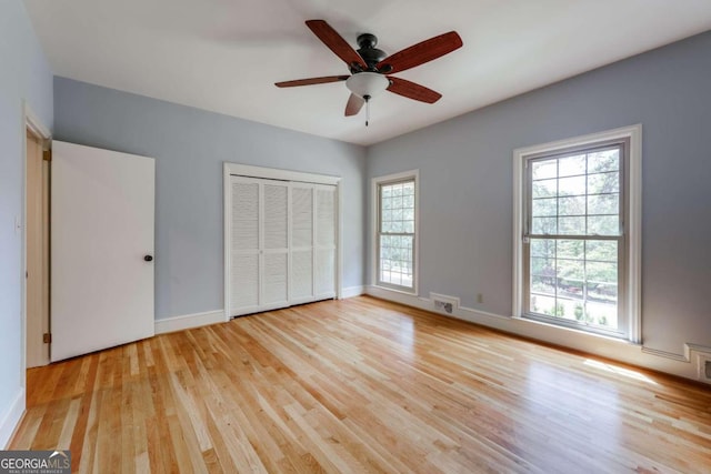 unfurnished bedroom with light wood-type flooring, ceiling fan, and a closet