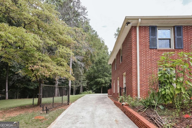 view of side of property with brick siding and fence