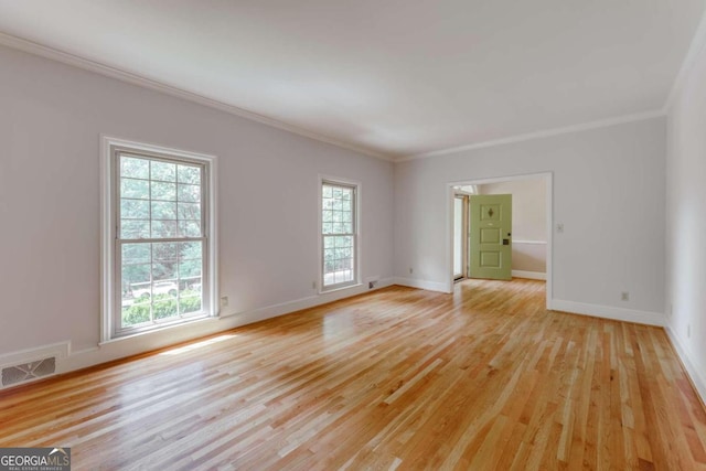 spare room with visible vents, light wood-style flooring, baseboards, and ornamental molding