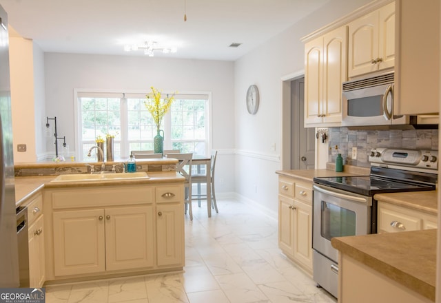 kitchen featuring backsplash, marble finish floor, appliances with stainless steel finishes, and a sink