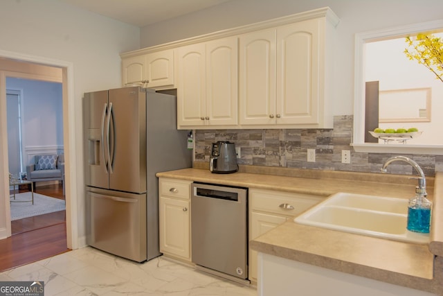 kitchen featuring a sink, light countertops, marble finish floor, appliances with stainless steel finishes, and tasteful backsplash